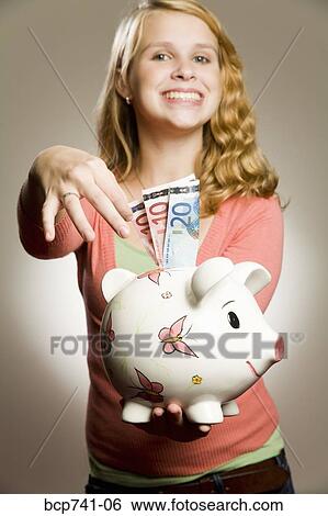 Teenage girl holding piggy bank with money View Large Photo Image Stock Photograph - Teenage girl holding piggy bank with money. Fotosearch