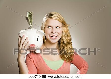 Teenage girl holding piggy bank with money View Large Photo Image Stock Photography - Teenage girl holding piggy bank with money. Fotosearch