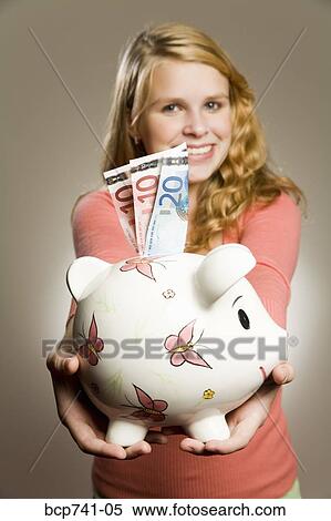 Teenage girl holding piggy bank with money View Large Photo Image Stock Photography - Teenage girl holding piggy bank with money. Fotosearch