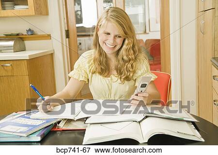 Teenage girl studying and looking at cell phone View Large Photo Image Stock Photo - Teenage girl studying and looking at cell phone. Fotosearch