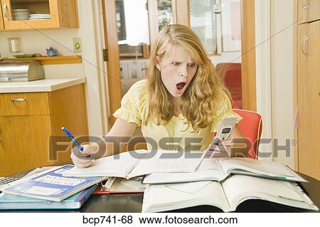 Stock Photo - Teenage girl studying and looking at cell phone. Fotosearch