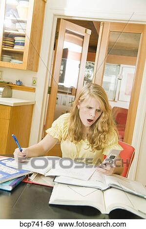 Teenage girl studying and looking at cell phone View Large Photo Image Stock Photo - Teenage girl studying and looking at cell phone. Fotosearch