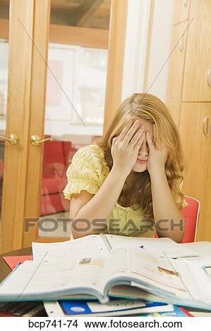 Teenage girl with hands on face in front of school books View Large Photo Image Picture - Teenage girl with hands on face in front of school books. Fotosearch