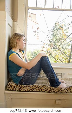 Stock Image - Teenaged girl looking out window. Fotosearch