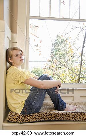 Teenaged girl sitting next to window View Large Photo Image Stock Image - Teenaged girl sitting next to window. Fotosearch