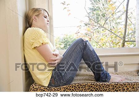 Teenaged girl sitting next to window View Large Photo Image Stock Photo - Teenaged girl sitting next to window. Fotosearch
