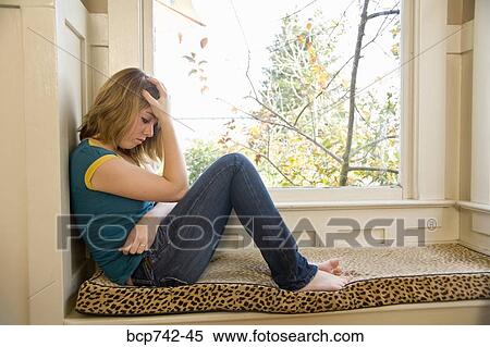 Teenaged girl sitting next to window View Large Photo Image Stock Photography - Teenaged girl sitting next to window. Fotosearch