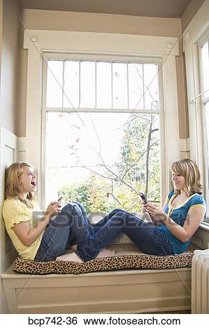 Teenaged sisters dialing cell phones View Large Photo Image Stock Photograph - Teenaged sisters dialing cell phones. Fotosearch