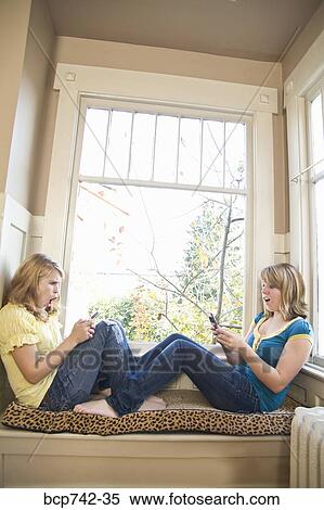 Teenaged sisters dialing cell phones View Large Photo Image Stock Photography - Teenaged sisters dialing cell phones. Fotosearch