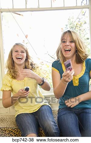 Teenaged sisters laughing with cell phones View Large Photo Image Stock Photo - Teenaged sisters laughing with cell phones. Fotosearch