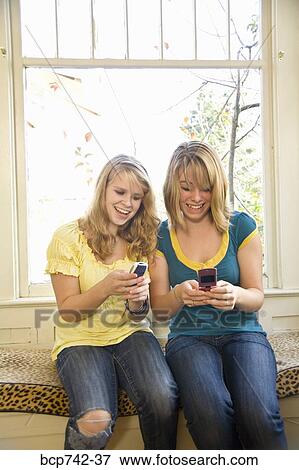 Teenaged sisters looking at cell phones View Large Photo Image Stock Photo - Teenaged sisters looking at cell phones. Fotosearch