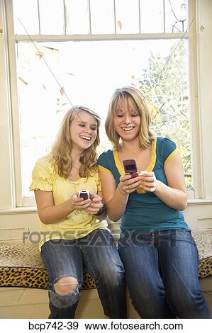 Teenaged sisters looking at cell phones View Large Photo Image Stock Photo - Teenaged sisters looking at cell phones. Fotosearch
