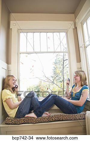 Teenaged sisters talking on cell phones View Large Photo Image Picture - Teenaged sisters talking on cell phones. Fotosearch