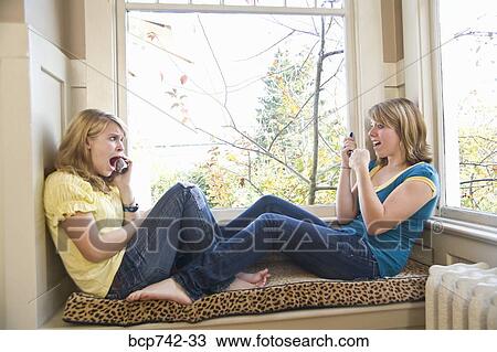 Teenaged sisters talking on cell phones View Large Photo Image Stock Image - Teenaged sisters talking on cell phones. Fotosearch