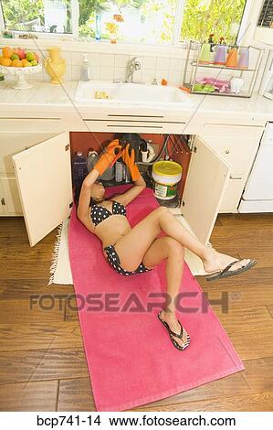 Woman in bikini fixing plumbing under sink View Large Photo Image Picture - Woman in bikini fixing plumbing under sink. Fotosearch