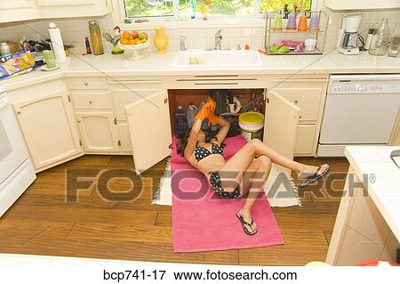 Woman in bikini fixing plumbing under sink View Large Photo Image Stock Photo - Woman in bikini fixing plumbing under sink. Fotosearch