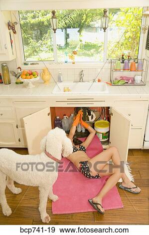 Woman in bikini fixing plumbing under sink View Large Photo Image Stock Photo - Woman in bikini fixing plumbing under sink. Fotosearch