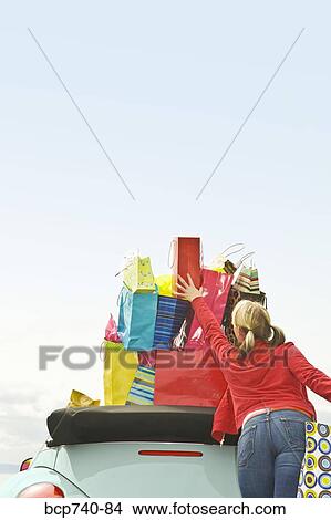 Woman reaching for shopping bag stack in car View Large Photo Image Picture - Woman reaching for shopping bag stack in car. Fotosearch