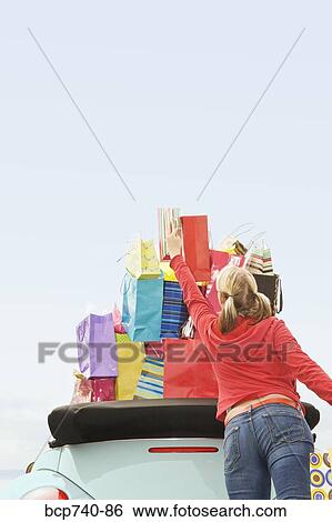 Woman reaching for shopping bag stack in car View Large Photo Image Stock Photograph - Woman reaching for shopping bag stack in car. Fotosearch