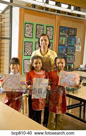 Stock Image - African art teacher and students holding paintings. Fotosearch