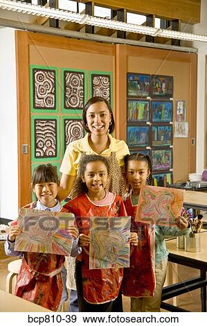 Stock Photo - African art teacher and students holding paintings. Fotosearch