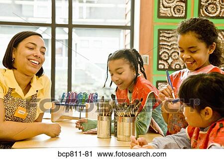 Stock Image - African female art teacher and students in classroom. Fotosearch