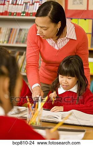 Picture - African female teacher helping student. Fotosearch