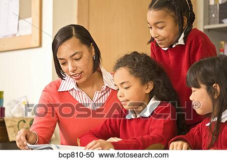 Stock Image - African female teacher helping students. Fotosearch