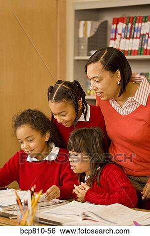 Stock Photograph - African female teacher helping students. Fotosearch