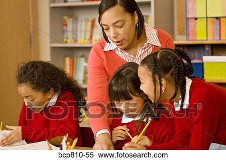 Stock Photography - African female teacher helping students. Fotosearch