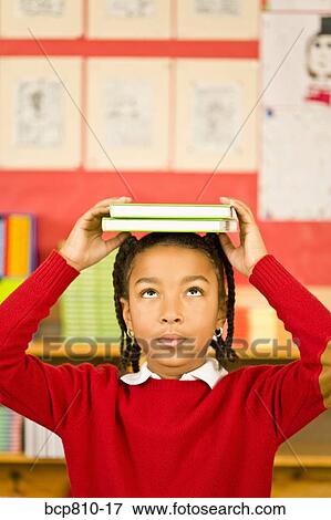 Stock Photo - African girl holding books on head. Fotosearch