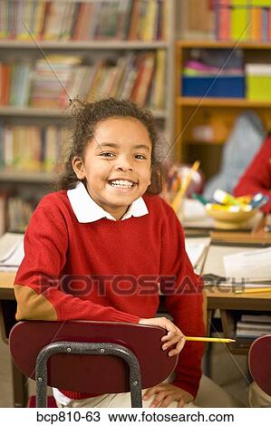 Stock Image - African girl sitting in school desk. Fotosearch