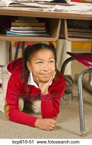 African girl sitting under school desk View Large Photo Image Stock Image - African girl sitting under school desk. Fotosearch
