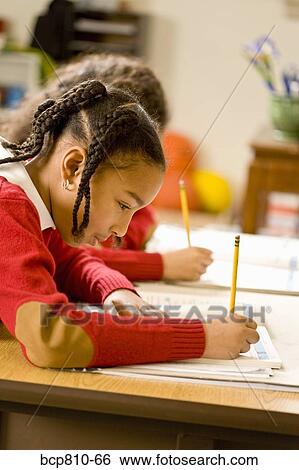 Stock Photograph - African girl writing at school desk. Fotosearch