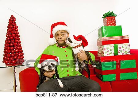 Stock Photo - African man and dogs wearing Santa Claus hats. Fotosearch