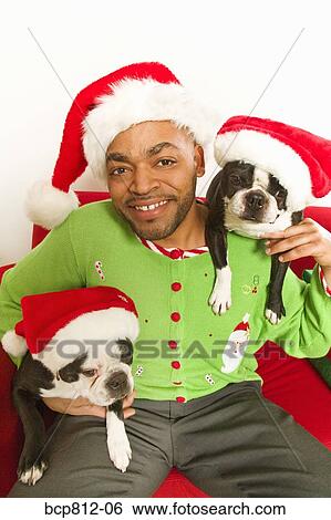 Stock Photograph - African man and dogs wearing Santa Claus hats. Fotosearch