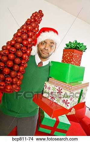 African man holding Christmas gifts and ornaments View Large Photo Image Picture - African man holding Christmas gifts and ornaments. Fotosearch