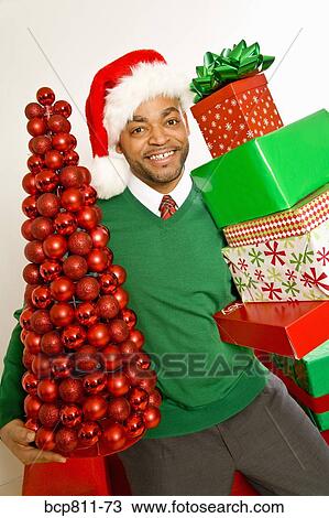 African man holding Christmas gifts and ornaments View Large Photo Image Stock Image - African man holding Christmas gifts and ornaments. Fotosearch