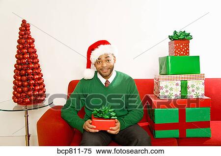 Stock Photography - African man next to stack of Christmas gifts. Fotosearch