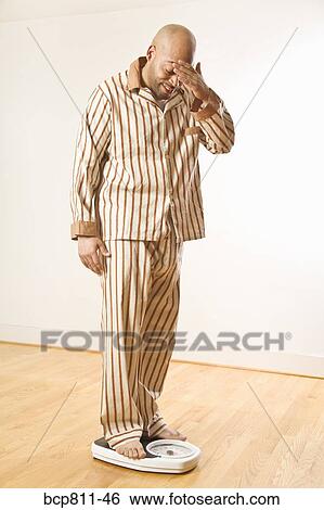 Stock Photograph - African man standing on scale. Fotosearch