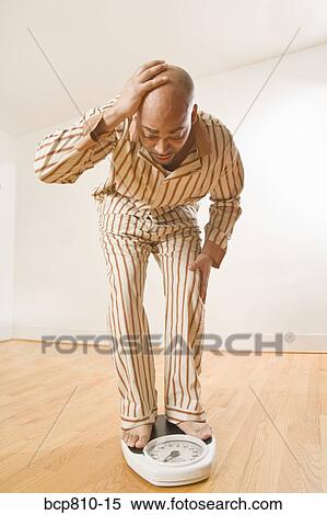 Stock Photography - African man standing on scale. Fotosearch