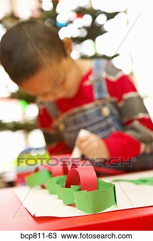 Stock Image - Asian boy making paper chain. Fotosearch