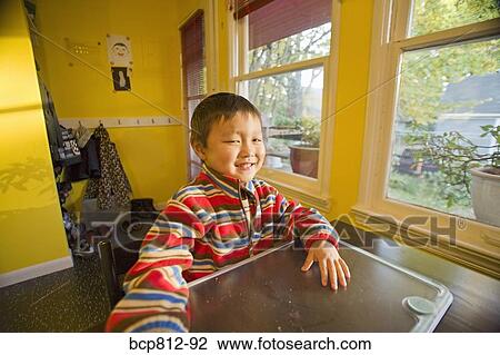 Stock Image - Asian boy sitting at table. Fotosearch