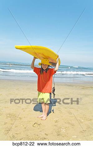 Asian girl holding surfboard on head View Large Photo Image Stock Image - Asian girl holding surfboard on head. Fotosearch