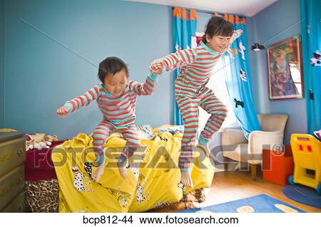 Asian siblings jumping off bed View Large Photo Image Picture - Asian siblings jumping off bed. Fotosearch
