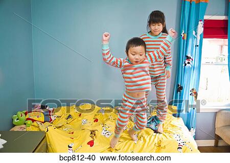 Asian siblings jumping on bed View Large Photo Image Stock Image - Asian siblings jumping on bed. Fotosearch