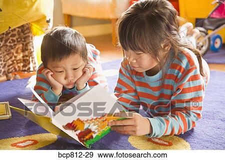 Stock Photo - Asian siblings reading book. Fotosearch