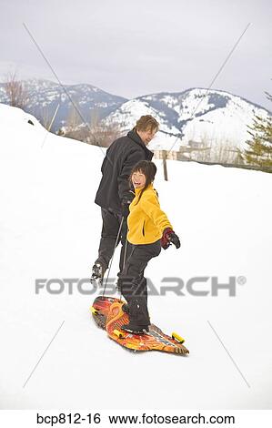 Father pulling daughter on sled View Large Photo Image Stock Photograph - Father pulling daughter on sled. Fotosearch