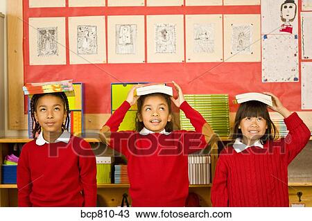 Multi-ethnic girl balancing school books on heads View Large Photo Image Stock Image - Multi-ethnic girl balancing school books on heads. Fotosearch