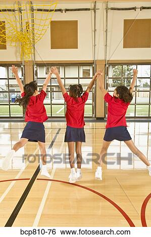 Stock Photograph - Multi-ethnic girls jumping in school gym. Fotosearch